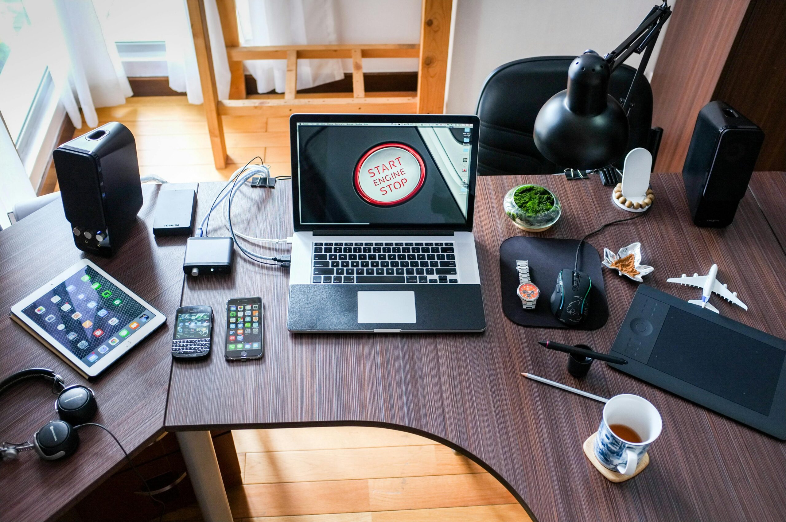 A contemporary office desk setup with laptops, gadgets, and accessories, creating a tech-savvy workplace.