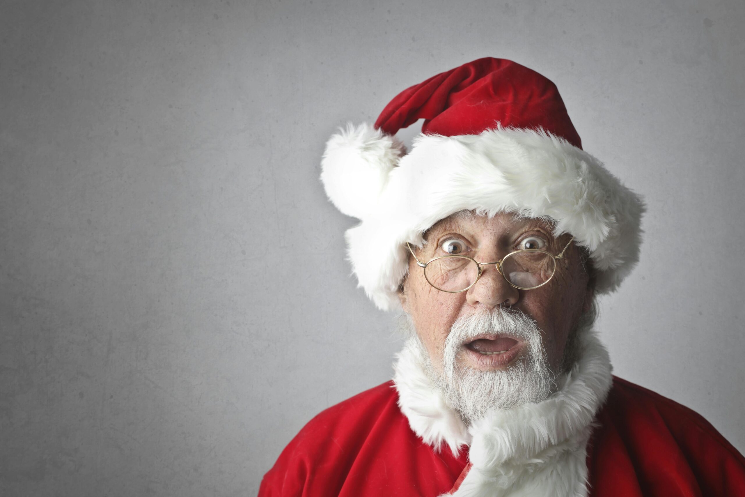 A surprised Santa Claus in traditional red outfit and glasses, expressing joy and wonder.